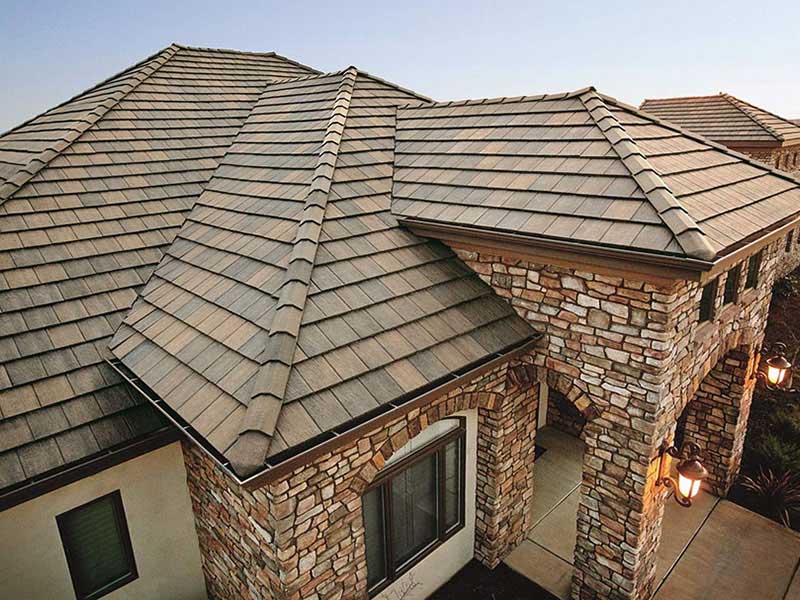 Close-up view of a residential home with a brown tile roof and brown rocky siding